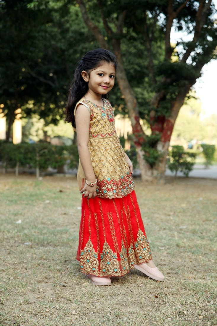 Girl in a gold and red garara suit made by Faraak garment factory Karachi